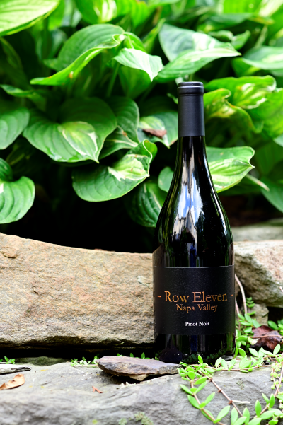 Photo of Row Eleven Napa Valley 2020 bottle next to foliage